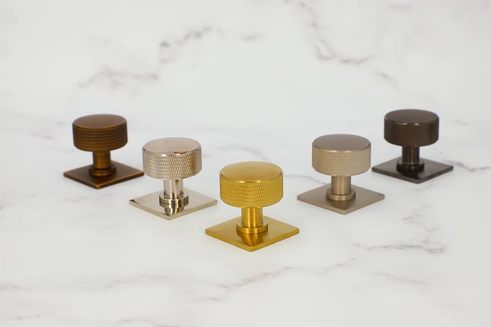 Alexander and Wilks Knurled Lucia Cupboard Knobs with Quantock Backplates on a Marble Background at More Handles