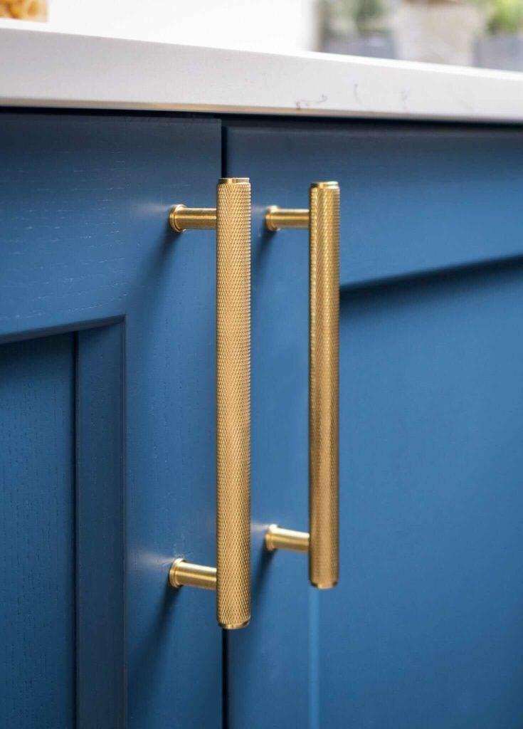 Knurled golden Crispin Cupboard handle on blue kitchen